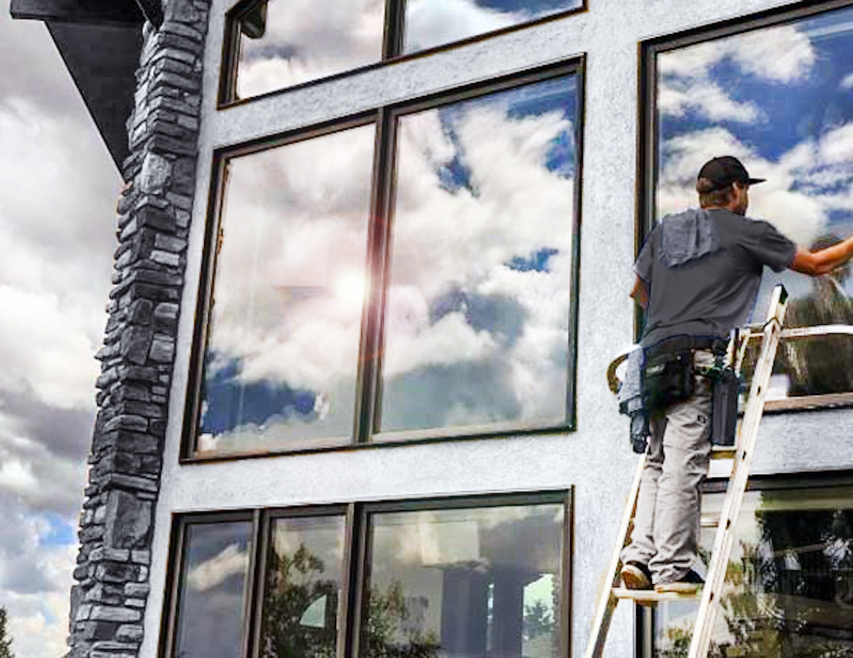 Window Cleaner crew member washing windows on ladder
